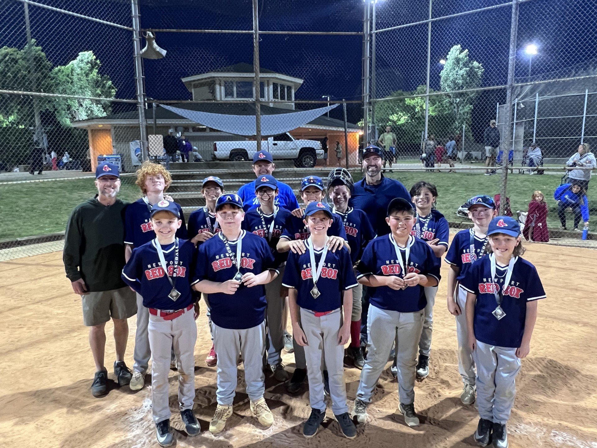 Youth baseball team celebrating with medals on the field.
